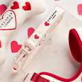 Cream knitted dog lead by Cocopup London with red heart pattern, displayed on a white marble surface.