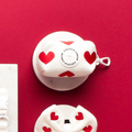 White harness, leash, and knitted poop bag holder with red heart prints from Cocopup London.