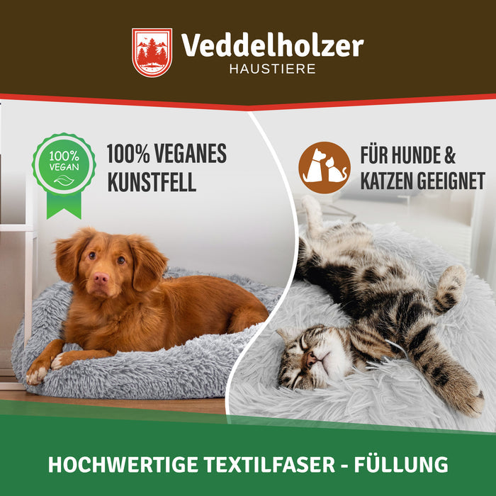 Brauner Toller liegt im hellgrauen Bett, rechts wälzt sich eine getigerte Katze – Hinweis auf vegane Kunstfaser-Füllung