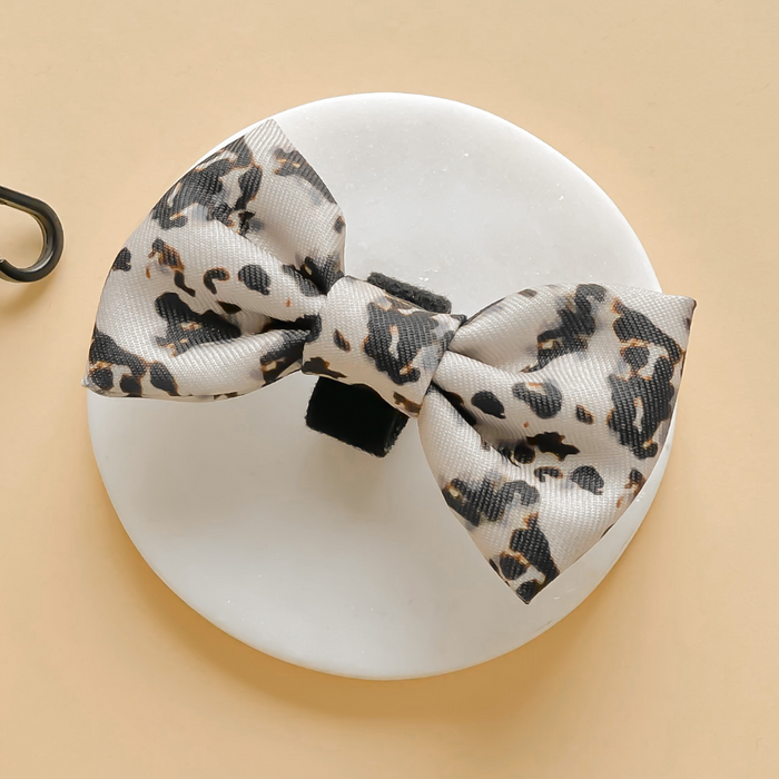 Ivory tortoiseshell-patterned bow tie by Cocopup London on a round white dish, beige background.