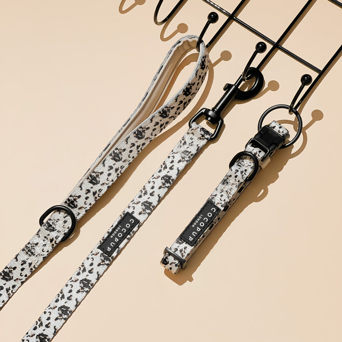 Ivory tortoiseshell-patterned dog lead with padded neoprene handle, hanging on black hooks.
