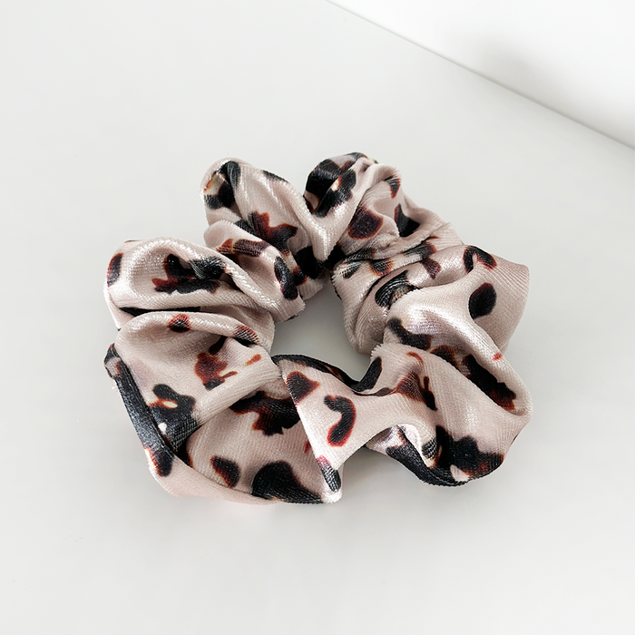 Ivory tortoiseshell-patterned scrunchie on a white surface.