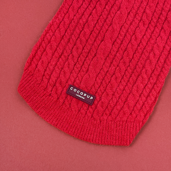 Red cable knit dog jumper by Cocopup London, displayed on a matching red background.