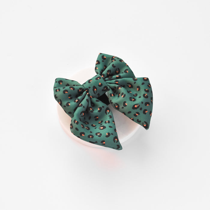 Khaki green sailor bow tie with black and orange leopard spots, displayed on a white dish against a white background.