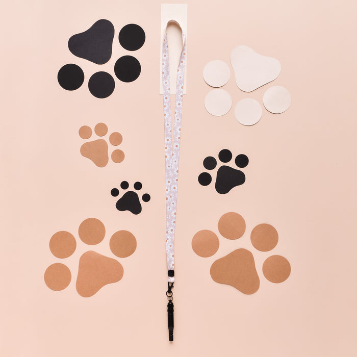 White Daisy Chain lanyard by Cocopup London on pale pink background with colorful paper paw prints.