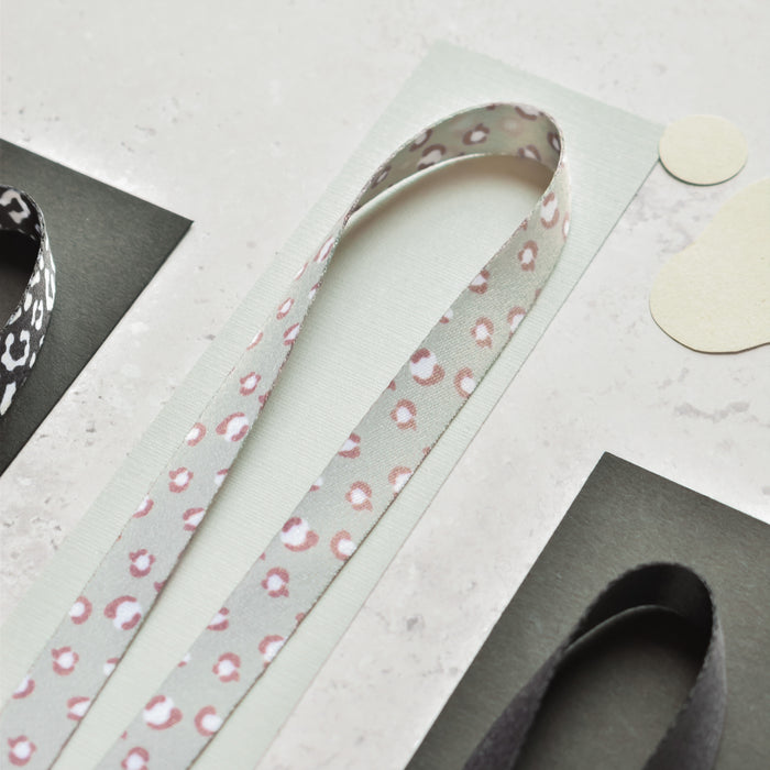 Three green leopard print Cocopup London lanyards looped on textured paper with colored rectangular backgrounds.