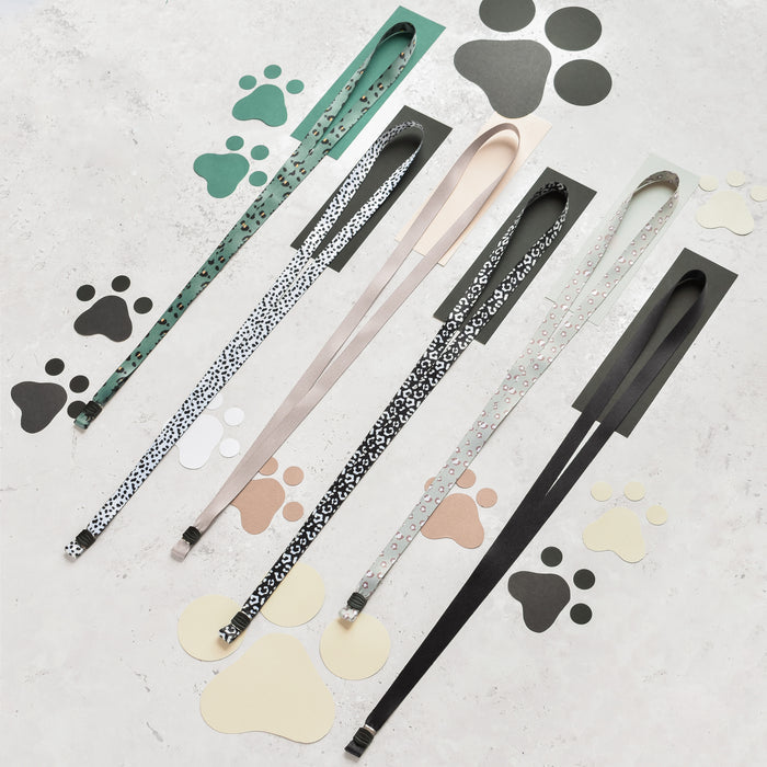 Five Cocopup London lanyards in assorted patterns, including Sage Leopard, arranged diagonally with paw print cutouts.
