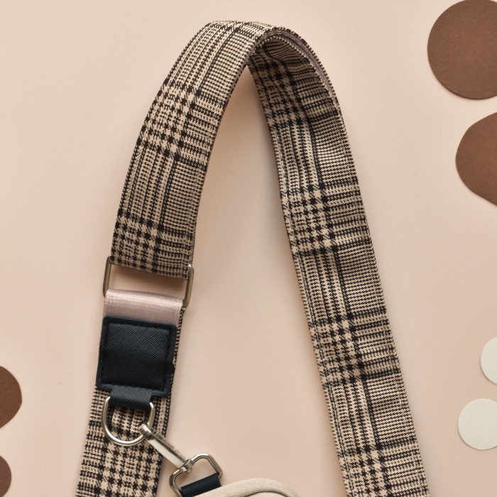 Black Cocopup London dog walking bag with a tan and black plaid strap and silver hardware.