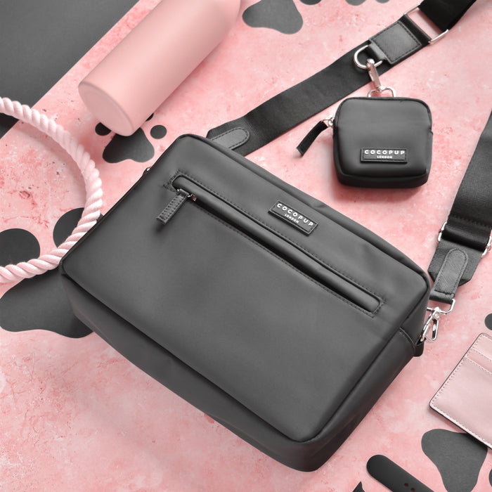 Black Cocopup London dog walking bag with matching pouch, pink rope leash, and accessories on a patterned surface.