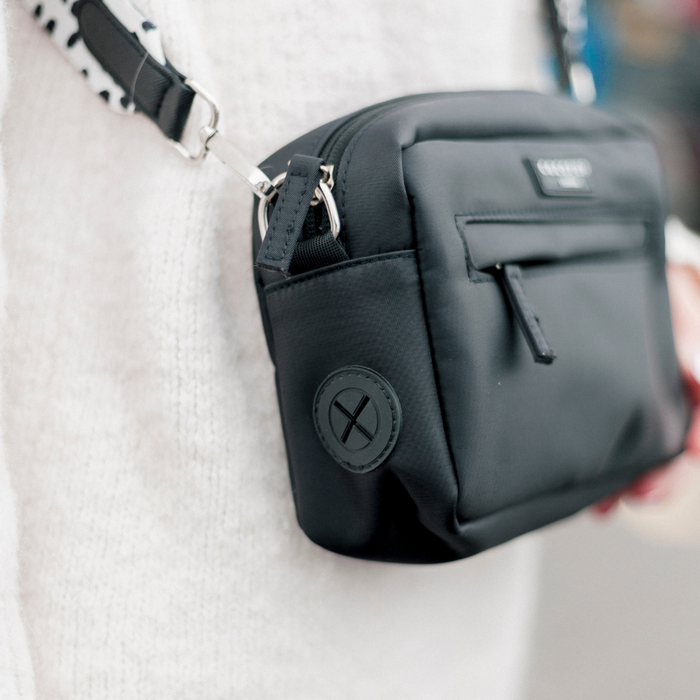 Person wearing a black Cocopup London large dog walking bag with a front zip pocket and a patterned shoulder strap.