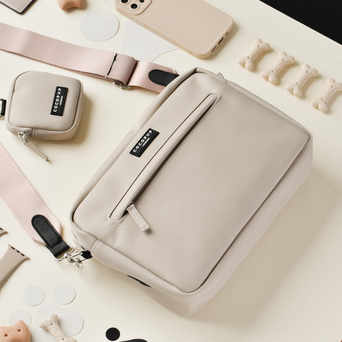 Caramel latte Cocopup London large dog walking bag with treats, phone, and accessories on a cream surface.
