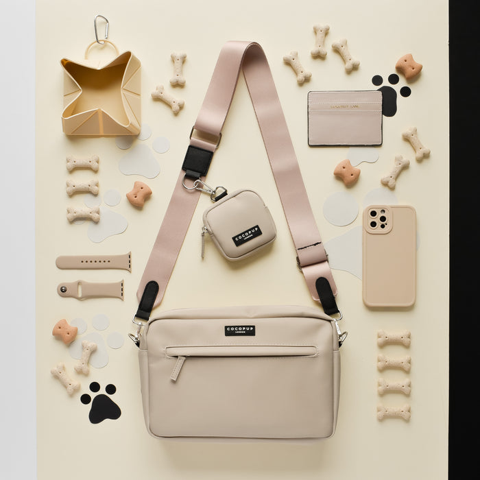 Cocopup London Large Dog Walking Bag in Caramel Latte with treats and accessories on a cream and black surface.