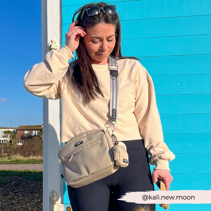 Woman with long dark hair holds a caramel brown Cocopup London dog walking bag with built-in poop bag dispenser.