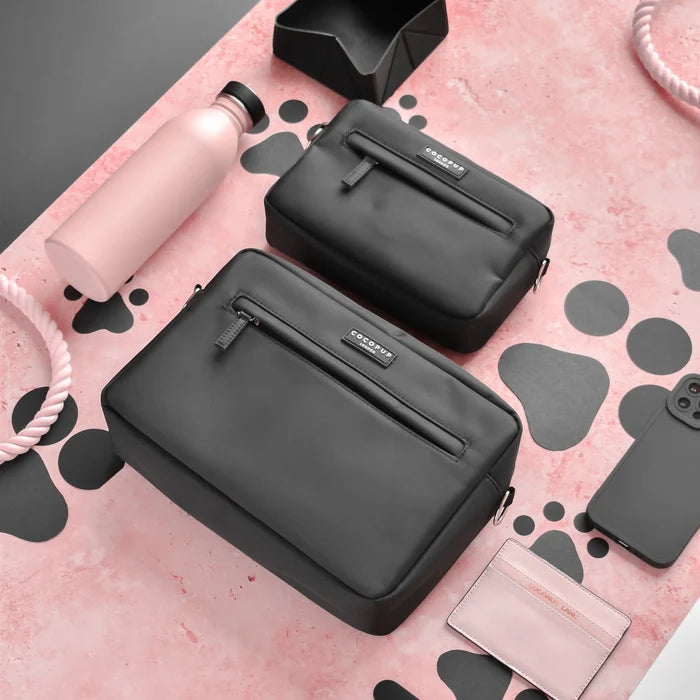 Two black Cocopup London dog walking bag bundles with case, treat pouch, and rope toy on a pink background with paw prints.