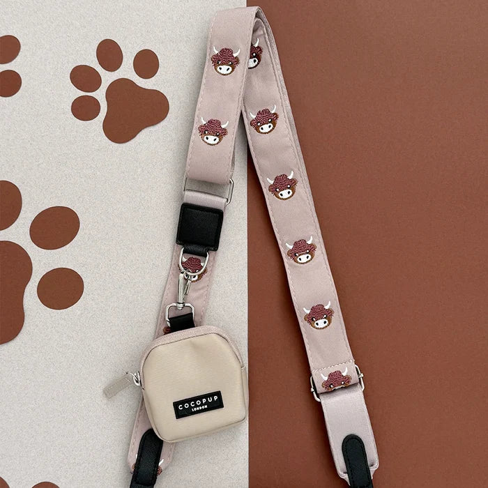 Large caramel latte dog walking bag with beige crossbody strap featuring Harold the Highland Cow design.