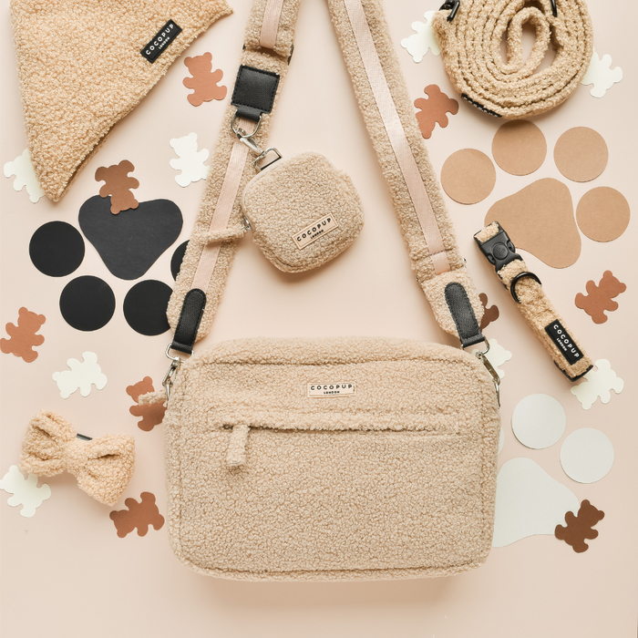 Teddy Rupert dog walking bag set in soft beige, includes bow, leash, collar, and treat pouch on a light background.
