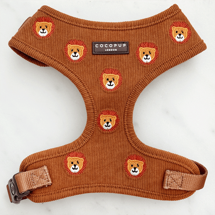 A brown / orange corduroy dog harness with embroidered lion faces.