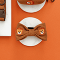 A brown / orange corduroy dog bow tie with embroidered lion faces. With velcro attachment.
