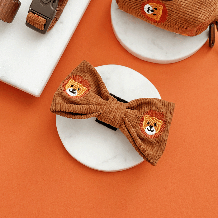A brown / orange corduroy dog bow tie with embroidered lion faces. With velcro attachment.