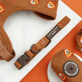 A brown / orange corduroy dog collar with embroidered lion faces.