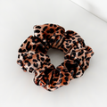 Leopard print fabric scrunchie with Cocopup London tag on a white surface.