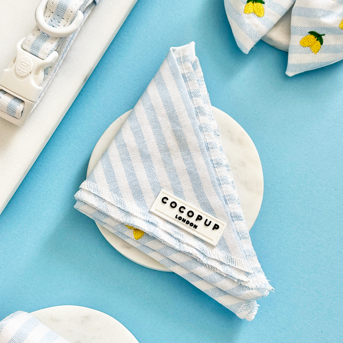 Yellow lemon-patterned dog bandana by Cocopup London displayed on a round marble coaster.