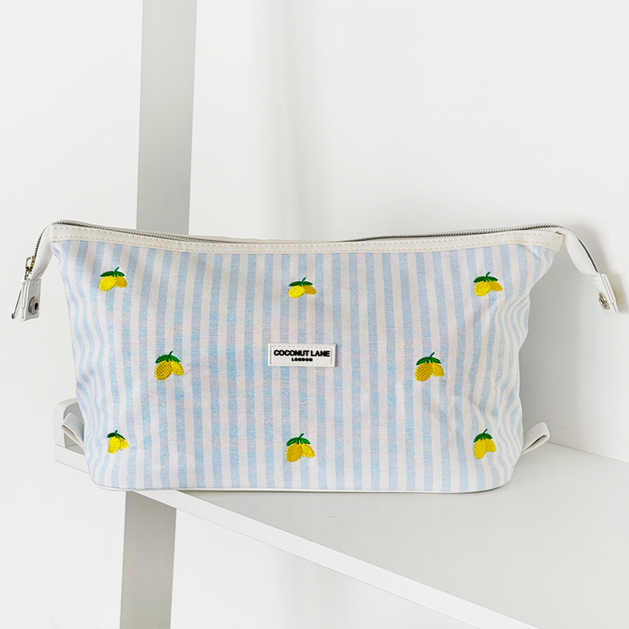 Expandable makeup bag with blue stripes and lemon print, by Cocopup London, displayed on a white shelf.