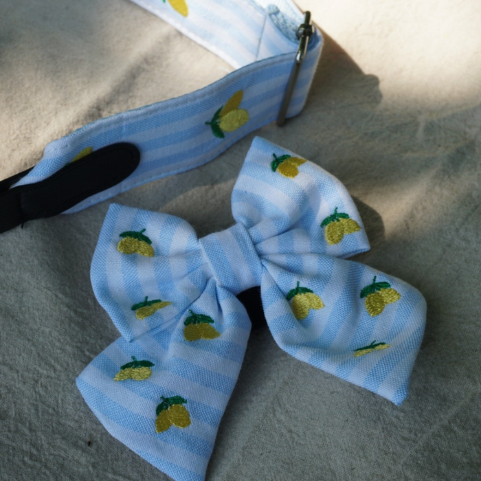 Blue and white striped sailor bow tie with lemon pattern by Cocopup London, displayed on a cream surface.