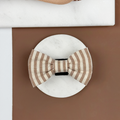 Brown and beige striped dog bow tie on a brown background.