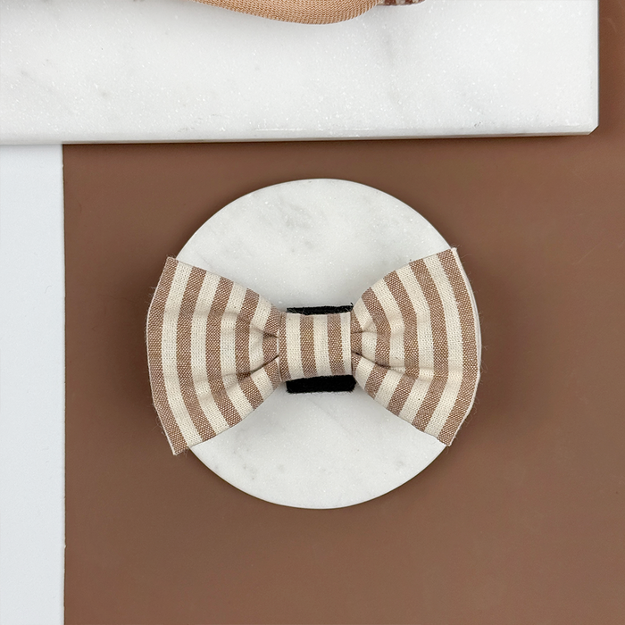 Brown and beige striped dog bow tie on a brown background.
