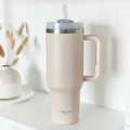 Marshmallow pink stainless steel tumbler with handle, lid, and straw by Cocopup London on a shelf.