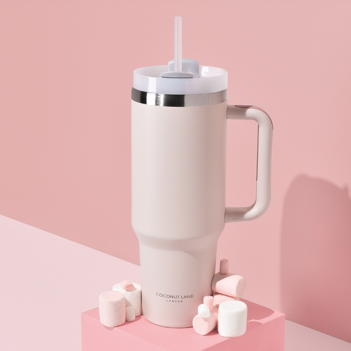 Marshmallow pink stainless steel tumbler with handle and straw, shown on a matching pink background.