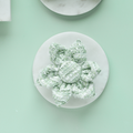 Cocopup London matcha green textured tweed collar flower on white, set against a light green background.