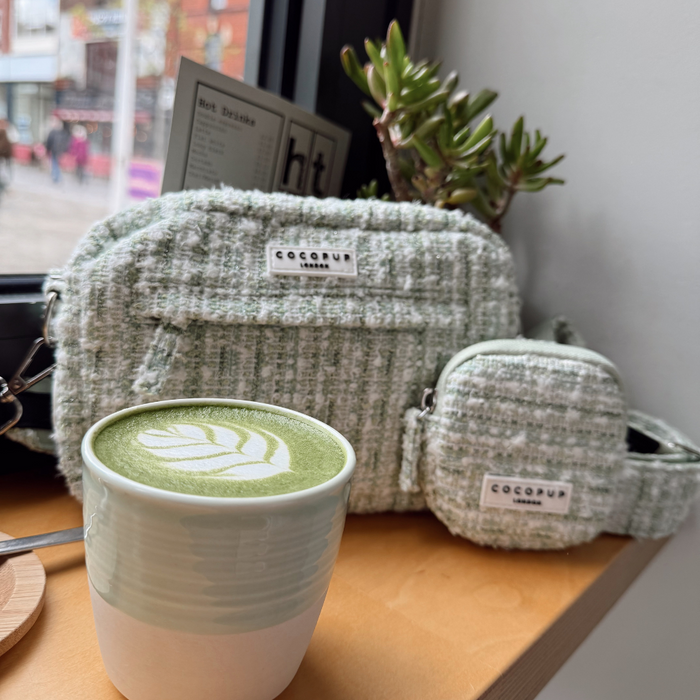 Matcha green textured tweed treat pouch from Cocopup London next to a matcha latte and a small potted plant.