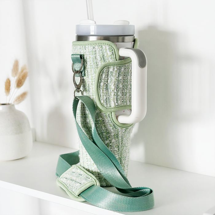 Green tweed tumbler carry case with a textured finish, white handle, and detachable crossbody strap.