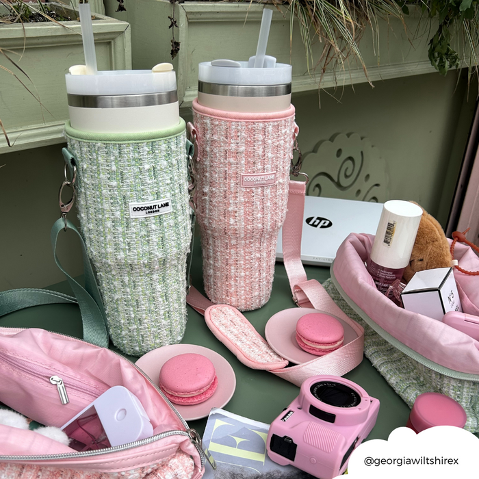 Two large Cocopup London bottles in green tweed tumbler cases, surrounded by macarons and pink accessories.
