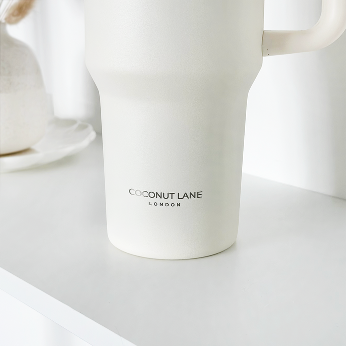Milky white stainless steel tumbler with Cocopup London logo on a white surface next to a small vase.