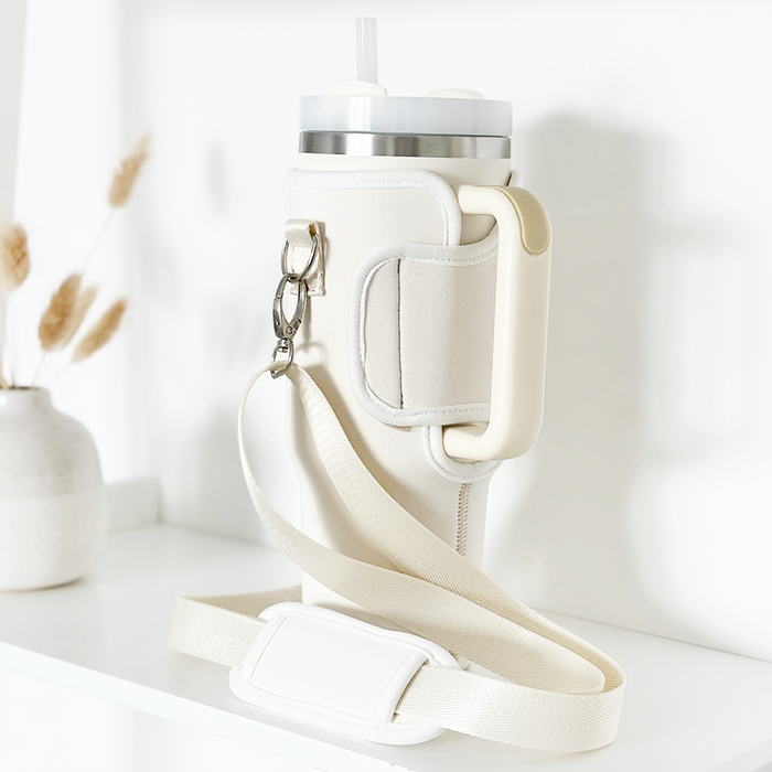 Cream tumbler with straw inside a beige Coconut Lane carry case, displayed on a white shelf.