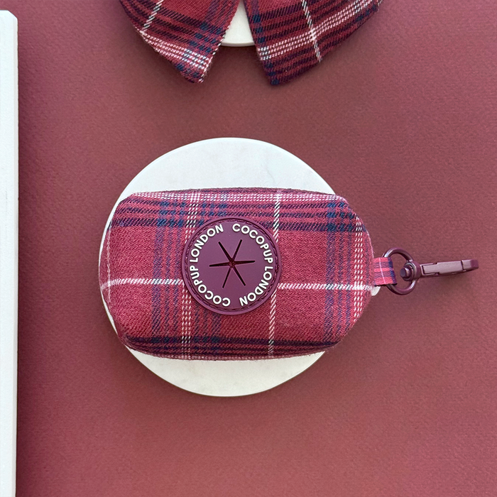 Red plaid Cocopup London Mulberry Poop Bag Holder with round logo, shown on a burgundy background.