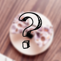 Cocopup London Mystery Bow Tie overlay on a blurred food plate, drawn question mark on wood background.
