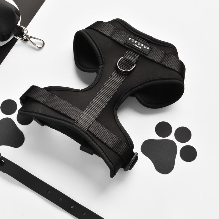 Black adjustable dog harness with white paw prints and matching leash set.