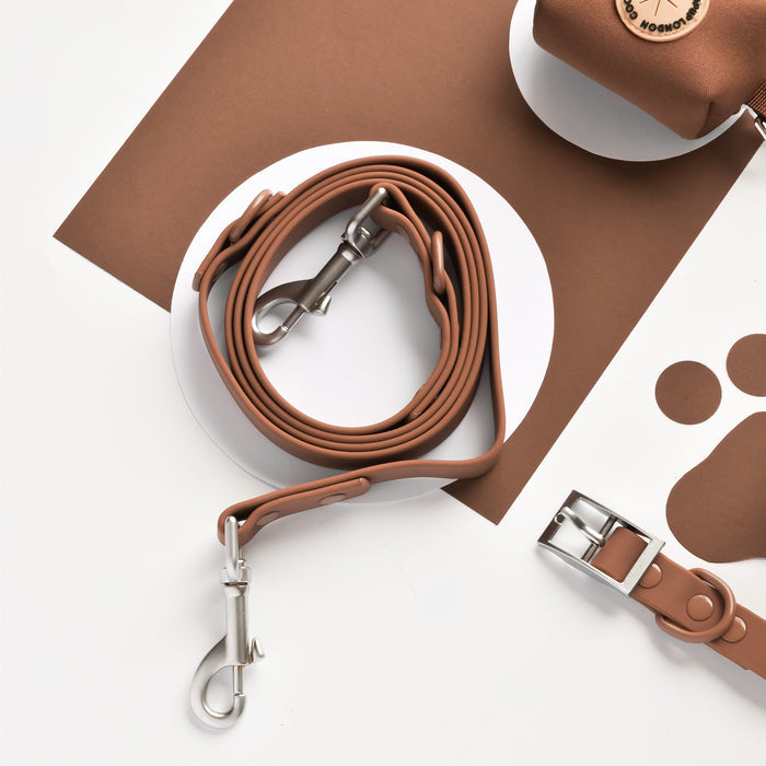Brown Cocopup London NAKD adjustable harness, leash, collar, and poop bag holder displayed on a white and brown backdrop.