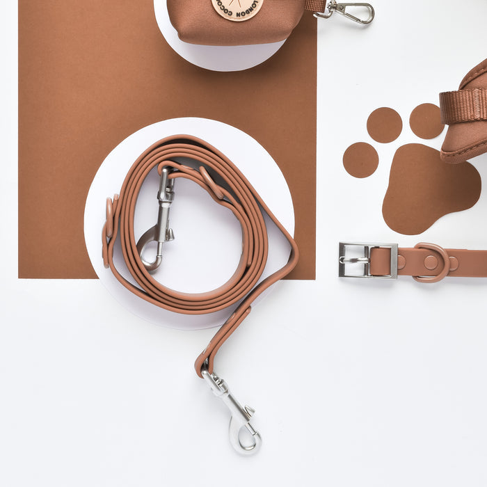 Brown dog lead with paw print cutout, laid flat on a white background.