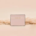 Beige NAKD Nude card holder with gold Coconut Lane text on the front, set against a soft beige background.