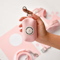 Hand holding a pink Cocopup London NAKD Poop Bag Holder with visible brand logo.