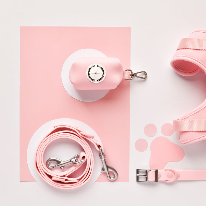 Candyfloss pink Cocopup London NAKD Poop Bag Holder with matching pink leash, harness, and collar on pink and white paper.