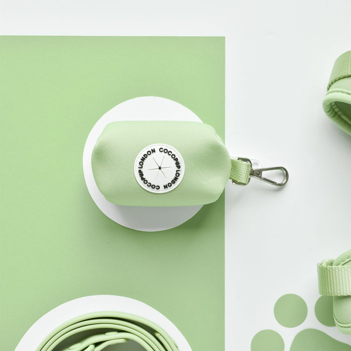 Small Matcha green Cocopup London poop bag holder with metal clip on a green and white circle-patterned background.