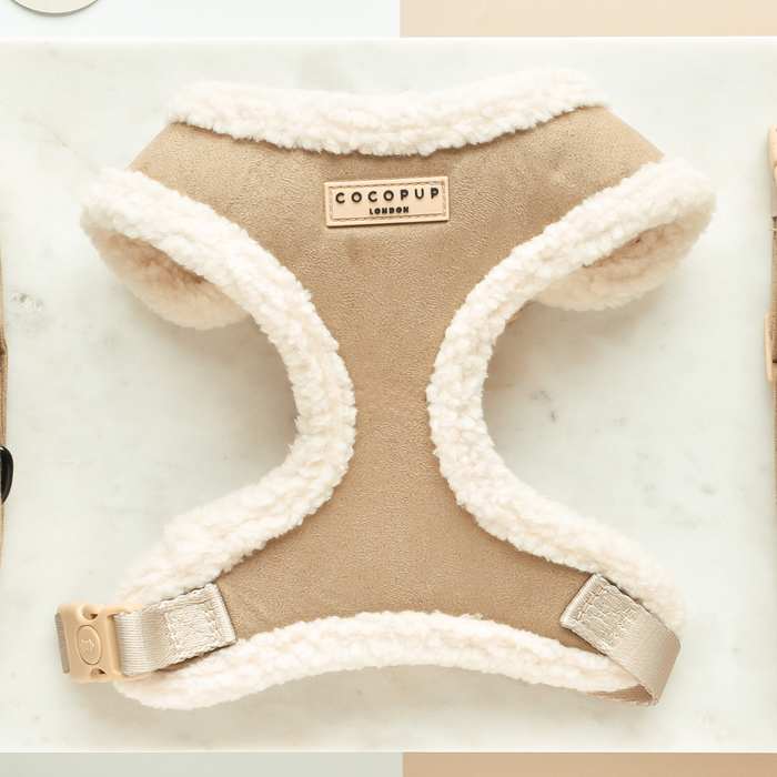 Nude adjustable neck harness with fluffy edges by Cocopup London, displayed on a marble surface.