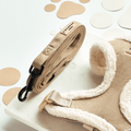Nude Aviator dog lead with faux suede handle and sherpa lining, displayed on marble with paw print confetti.