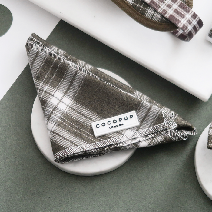 Olive green checkered bandana from Cocopup London displayed on a round white dish.